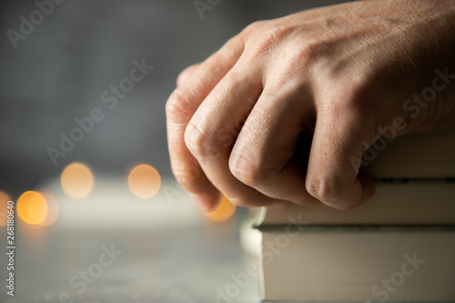 Dłoń leżąca na książkach na stole ze światełkami
