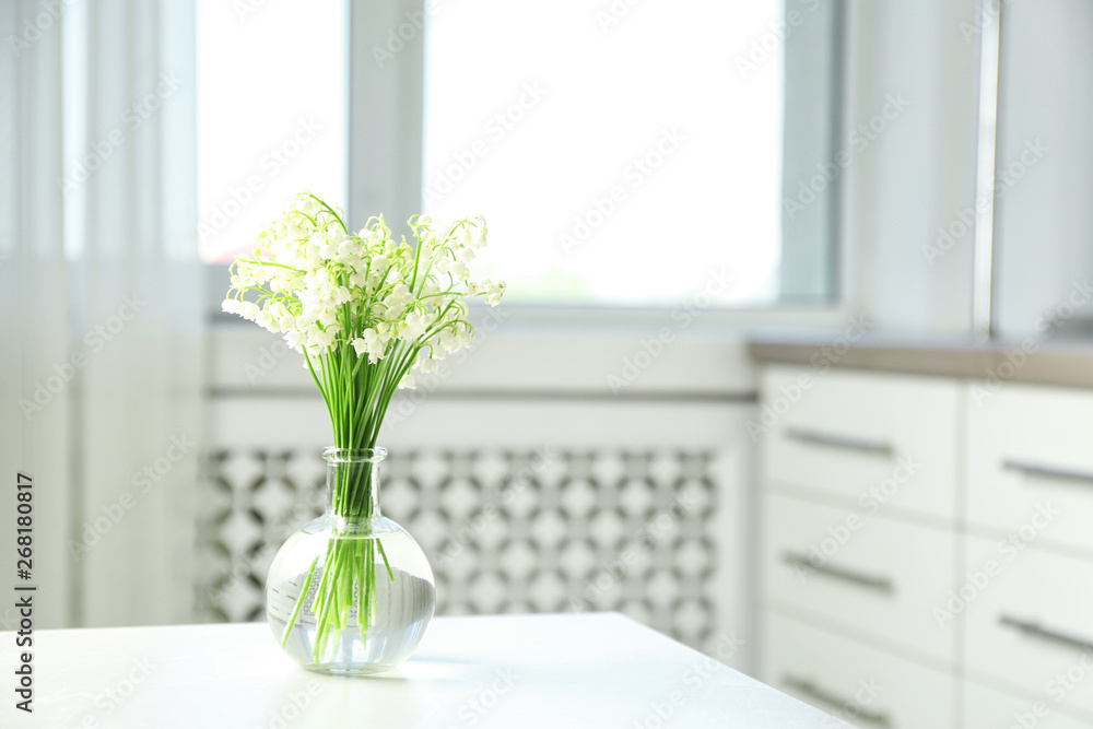 Vase with beautiful lily of the valley bouquet on table in room, space for text Vase with beautiful lily of the valley bouquet on table in room, space for text