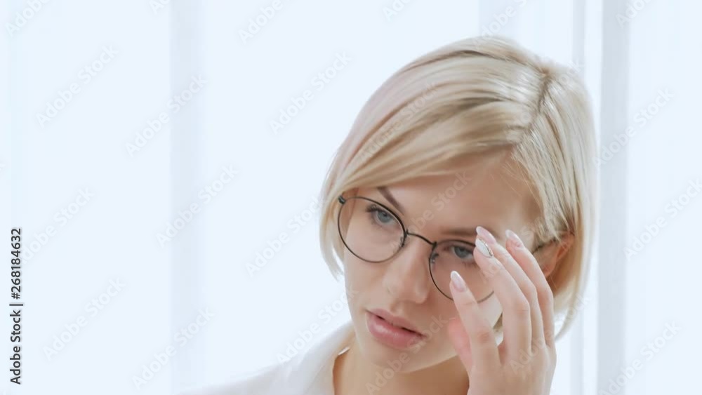 Young beautiful woman blonde with short hair in glasses on a white background. Clever and elegant, rejoices at the victory and carefully looks. Office life, businesswoman. Young beautiful woman blonde with short hair in glasses on a white background. Clever and elegant, rejoices at the victory and carefully looks. Office life, businesswoman.