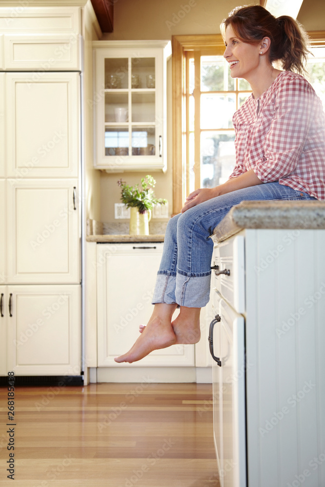 Portrait of woman in her 30's sitting on counter in kitchen at home Portrait of woman in her 30's sitting on counter in kitchen at home