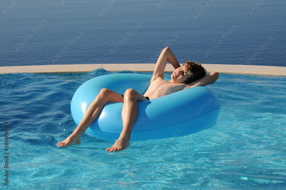 Boy floating in rubber ring in swimming pool on holiday