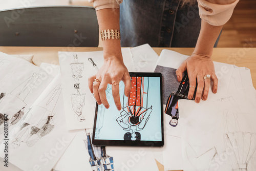 Young female fashion designer uses her tablet to make fashion sketches