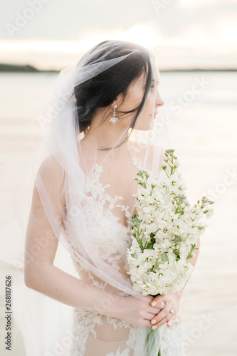 Wonderful bride in veil with floral bouquet