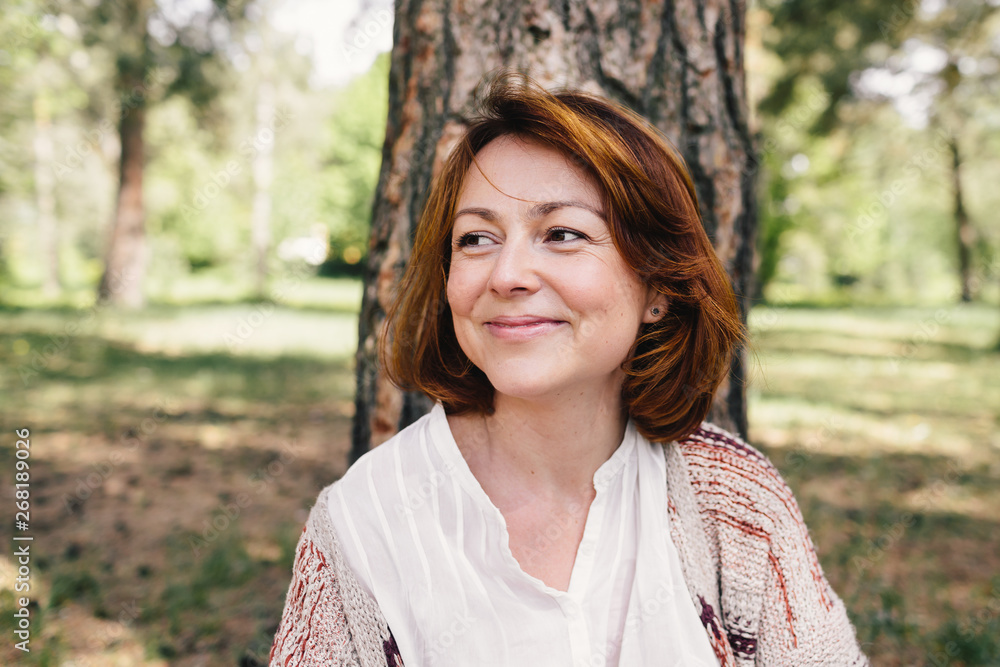Beautiful ginger woman sitting under the pines Beautiful ginger woman sitting under the pines