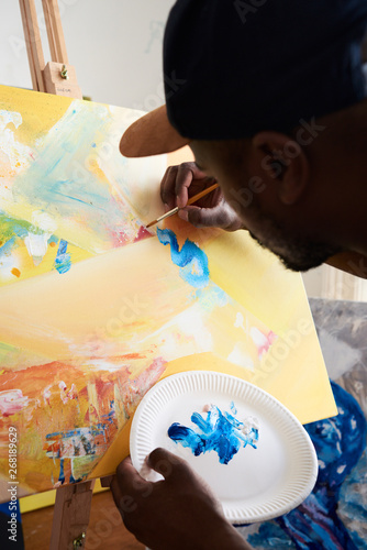 An artist painting strokes on canvas at his studio. photo