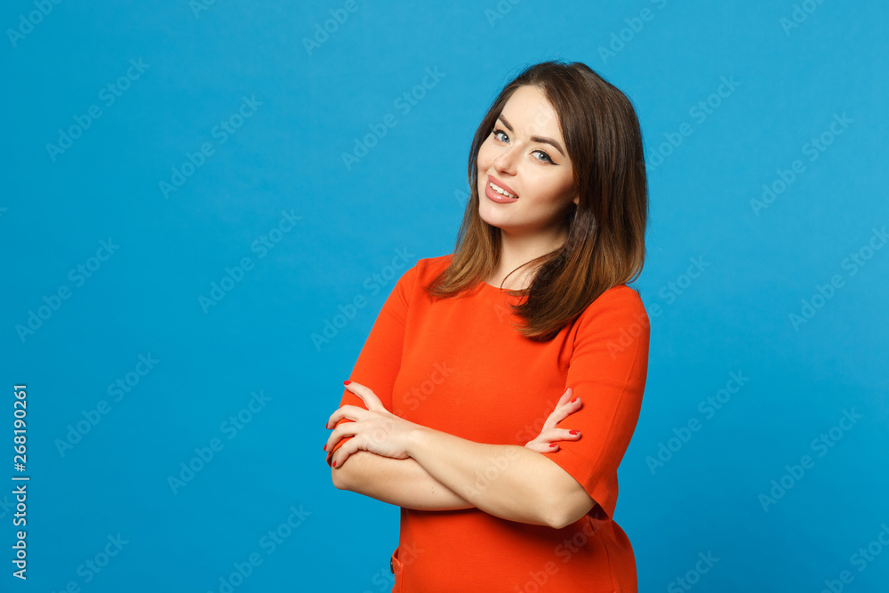 Beautiful brunette young woman wearing red dress looking camera standing posing folded hands isolated over blue wall background, studio portrait. People lifestyle fashion concept. Mock up copy space. Beautiful brunette young woman wearing red dress looking camera standing posing folded hands isolated over blue wall background, studio portrait. People lifestyle fashion concept. Mock up copy space.