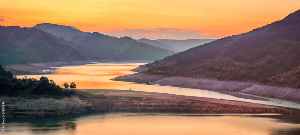 Fototapeta premium Amazing view of curvy, meandering Zavoj lake on Old mountain at golden hour during it's minimal water level panorama
