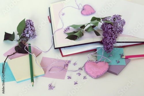 Fototapeta Naklejka Na Ścianę i Meble -  Open books, bookmarks hearts, paper, pencils, branches of lilac flowers on the table, read romantic books and write down your thoughts