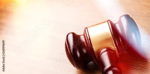 Wooden gavel on wooden table, on background