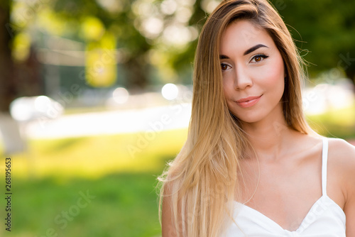 Fototapeta Naklejka Na Ścianę i Meble -  Beautiful gentle woman white dress happy smiling. Free space for text. Summer park in fresh air. The concept tenderness comfort accord confidence. Emotions of pleasure of beauty and smile.
