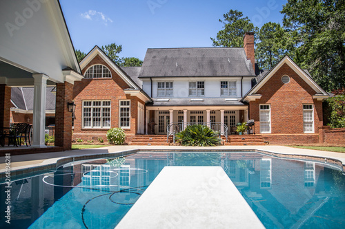 Large Blue Swimming Pool Outdoors with Brick Pool House and Home with pool Cleaner running © Ursula Page