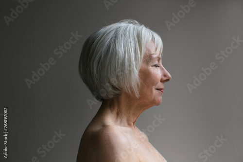 Senior topless woman on simple grey background photo