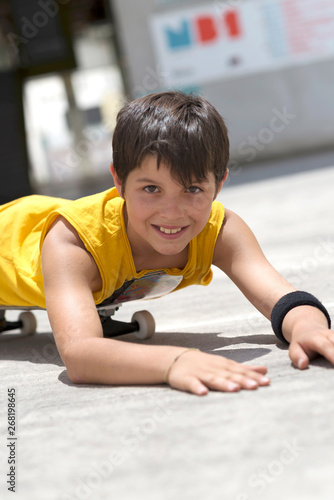 Young smiling boy on a skateboard while looking camera on a bright day