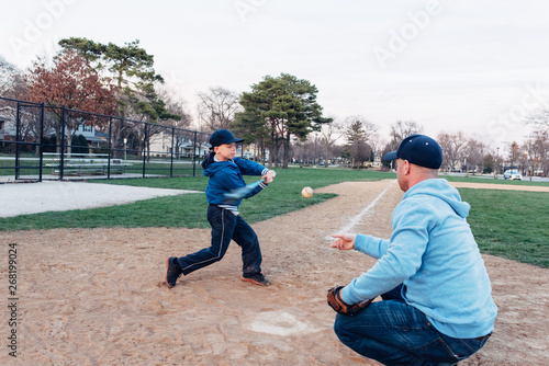 Father and son practicing hitting ball on a baseball field