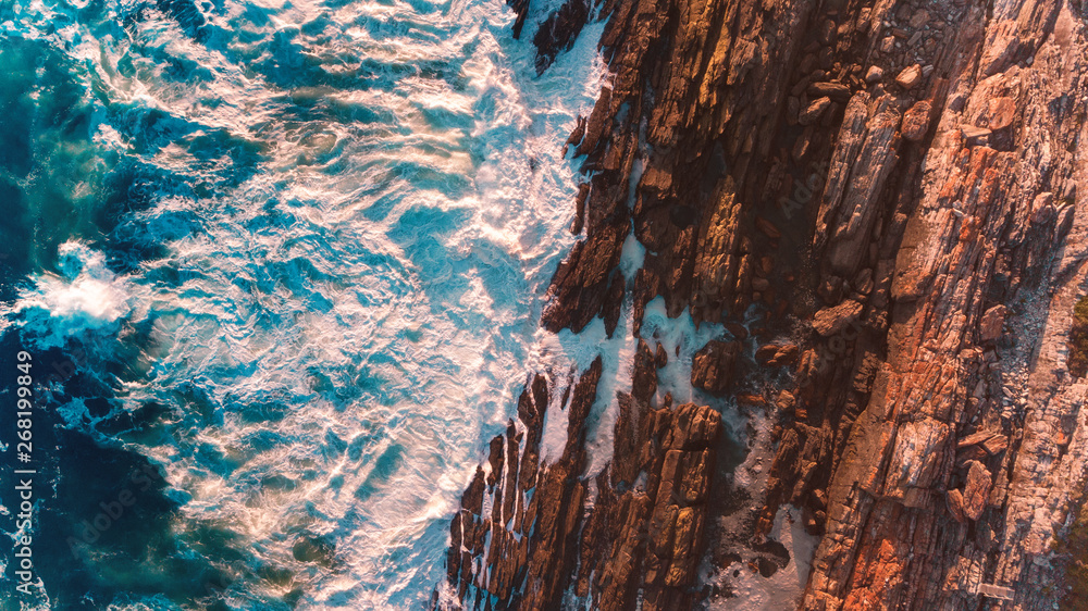 An aerial shot of the ocean shore and waves breaking the rocks An aerial shot of the ocean shore and waves breaking the rocks