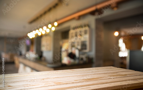 image of wooden table in front of abstract blurred background of resturant lights