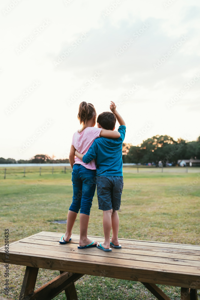 Children Watching The Sun Set On A Picnic Table Children Watching The Sun Set On A Picnic Table