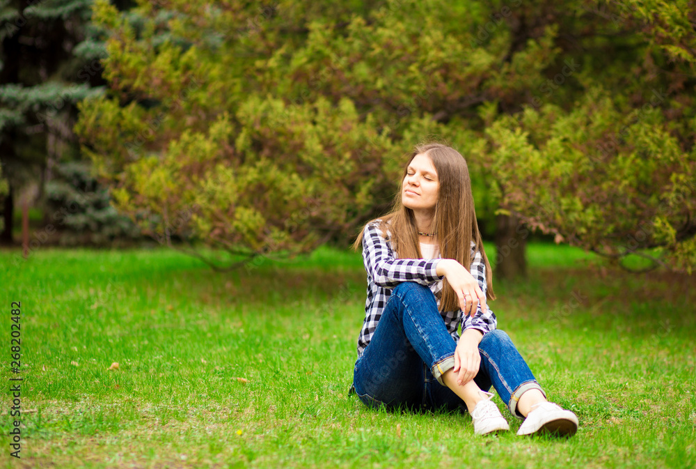 Fototapeta premium Attractive young woman enjoying her time outside in park with sunset in background.