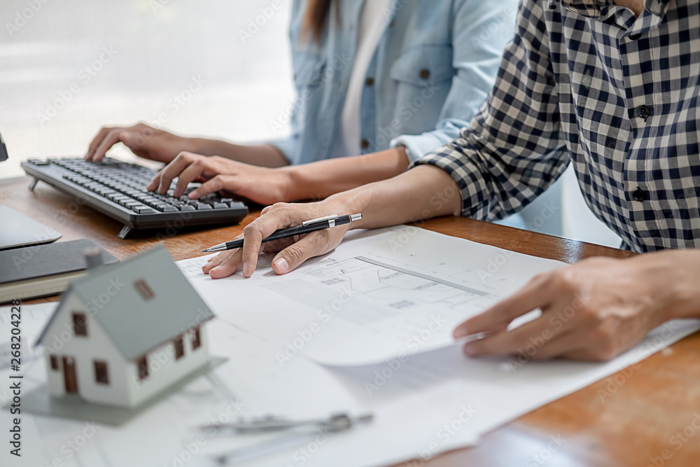 Engineers discuss a blueprint while checking information on a tablet computer in a office.