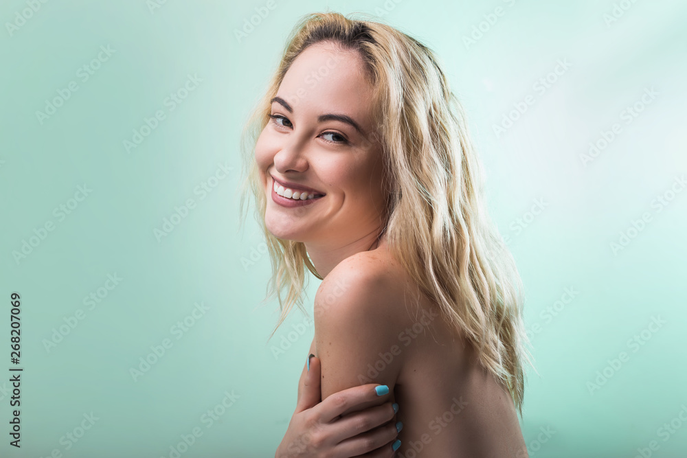 Fototapeta premium Beautiful young woman with curly blonde hair on green background