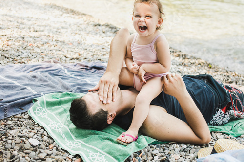 Little toddler sitting on her father's chest laughing photo