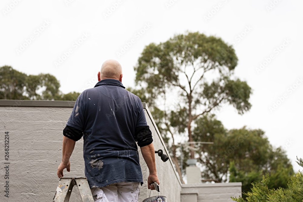 Painter at work on exterior of home in Australia Painter at work on exterior of home in Australia