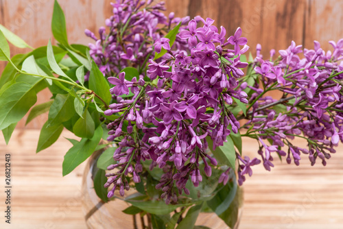 Wallpaper Mural Fresh cut Purple Lilac Flowers in clear glass vase on wooden background. Syringa vulgaris. Torontodigital.ca