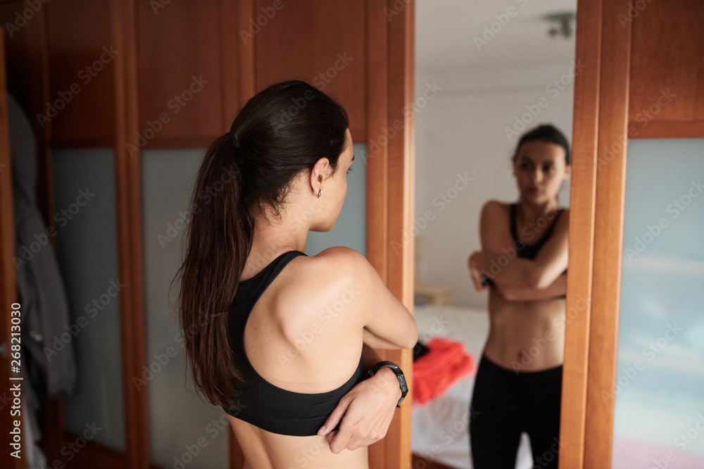 © guille Faingold/Stocksy - Woman Undressing Sports Bra At Home