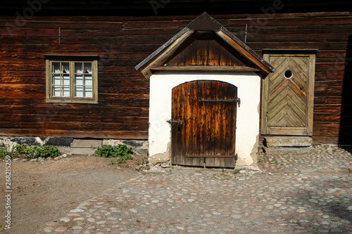 A detail of the old scandinavian wooden house. The house is old and looks shabby but still well maintained. One window can and the two entrance door can be seen.  photo