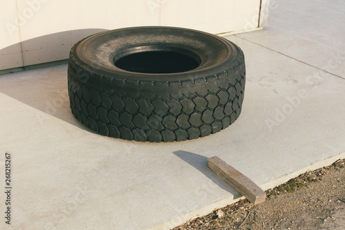 Discarded truck tire, circle of rusty metal and slab of wood on sidewalk photo