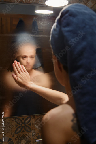 Woman wiping mirror in bathroom