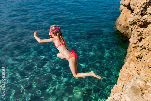 Kid jumping to the transparent sea