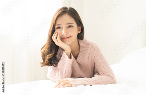 Portrait of young Asian woman smiling friendly and looking at camera in living room. Woman's face closeup. Concept woman lifestyle and winter. Autumn, winter season.