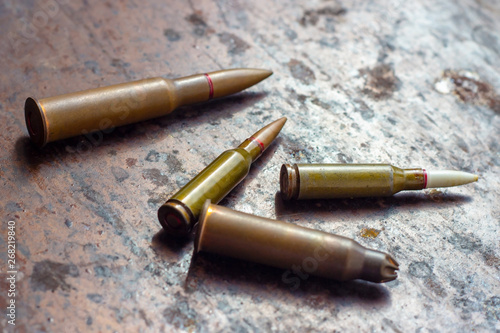 Weapon bullets on rusty metal background. Military industry, war, global arms trade and crime concept