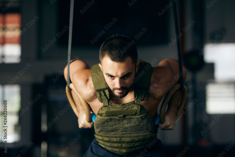 Muscle man training with rings in a gym. Stock Photo | Adobe Stock