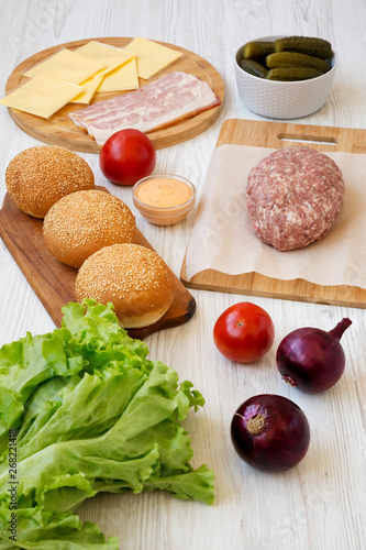 Cheeseburger ingredients on a white wooden table, side view. Close-up.