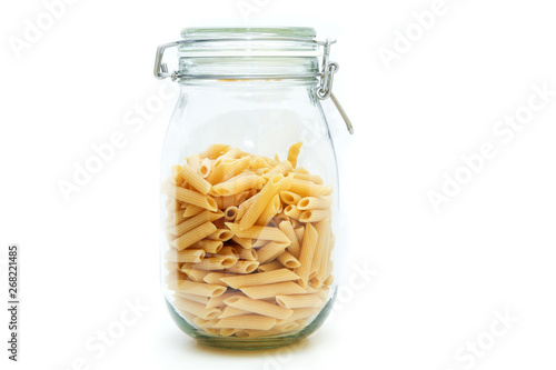 The dry penne pasta stored inside the closable glass bottle isolated on a white background.  photo