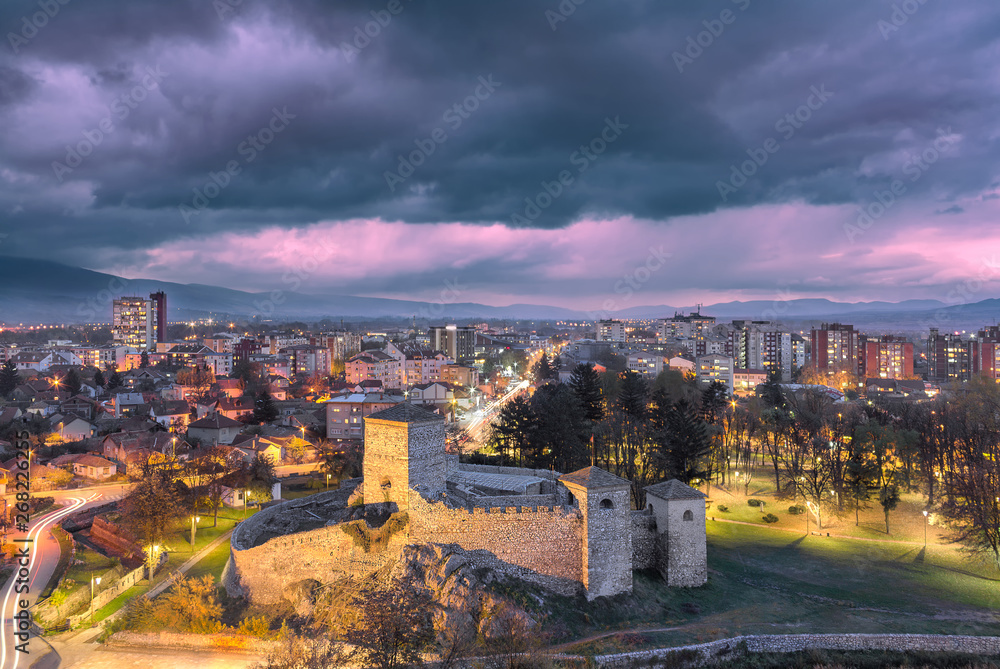 Blue hour Pirot cityscape with ancient 14th century fortress Momcilov grad in the foreground, purple sky and city lights