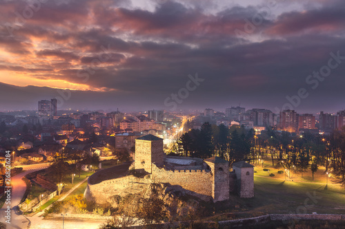 Sleepy Pirot blue hour cityscape and burning sunrise sky with iconic, ancient, foreground fortress 