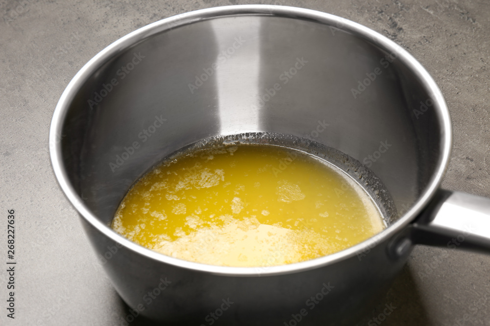 Saucepan with melting butter on grey table, closeup Saucepan with melting butter on grey table, closeup