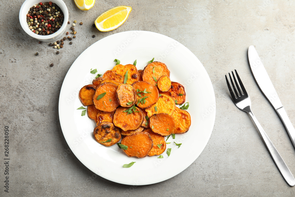 Plate with baked sweet potato slices served on grey table, top view Plate with baked sweet potato slices served on grey table, top view