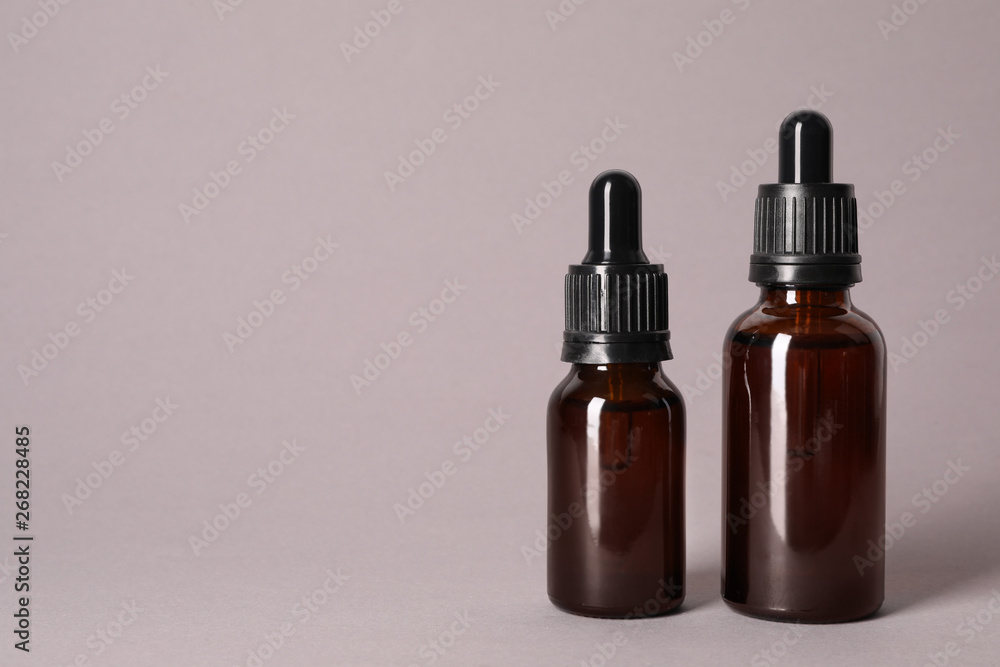 Cosmetic bottles of essential oils on color background. Space for text Cosmetic bottles of essential oils on color background. Space for text