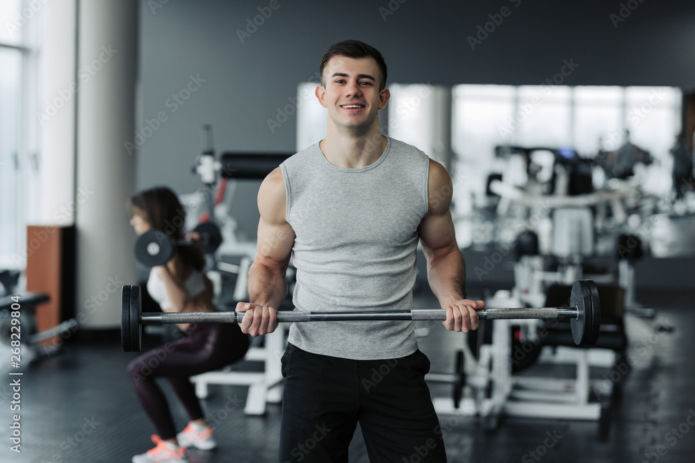 Handsome muscular man working out with dumbbells in the gym. Handsome muscular man working out with dumbbells in the gym.