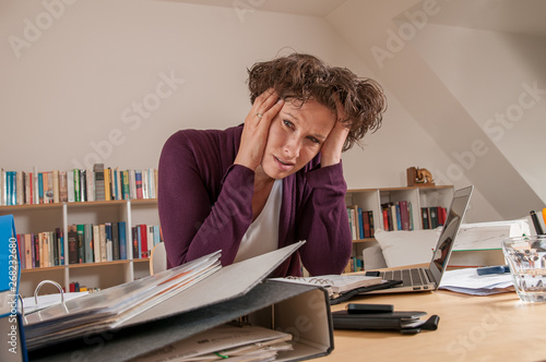 Stressed young woman in the office with too much work photo