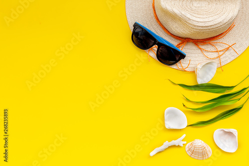 Planning vacation to the seaside with straw hat  sun glasses  shells on yellow background top view space for text