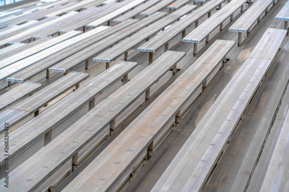 Obraz premium Close up of tiered rows of benches at a sports field viewed on a sunny day.