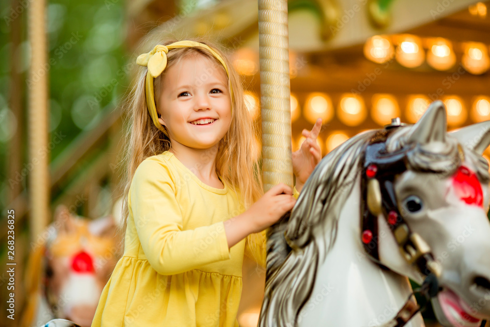 Εκτύπωση καμβά Adorable little girl near the carousel outdoors in Paris, baby girl on the carousel, Happy healthy baby child having fun outdoors on sunny day
