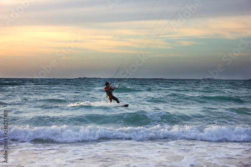 Young surfer rides the wave during sunset