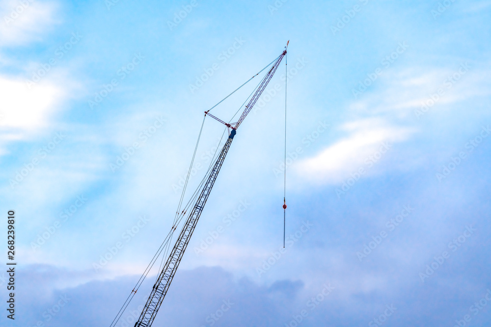 A lifting crane viewed against a beautiful blue sky filled with cottony clouds A lifting crane viewed against a beautiful blue sky filled with cottony clouds