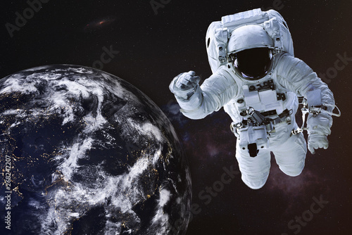 Fototapeta Naklejka Na Ścianę i Meble -  Astronaut in outer space with Earth planet of solar system. Science fiction wallpaper. Elements of this image were furnished by NASA